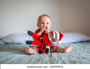 Cute, Adorable, Smiling, Happy Baby Dressed In Christmas Outfit Sitting On Bed.