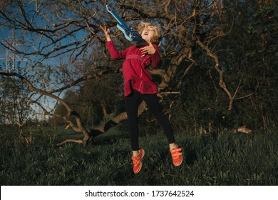 Cute Adorable Young Girl Playing Guitar Toy Outdoor. Girl Pretending To Be A Rock Music Star. Adorable Funny Child Having Fun In Park. Weird Funny Hilarious Authentic Candid Childhood Moments. 