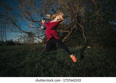 Cute Adorable Young Girl Playing Guitar Toy Outdoor. Girl Pretending To Be A Rock Music Star. Adorable Funny Child Having Fun In Park. Weird Funny Hilarious Authentic Candid Childhood Moments. 