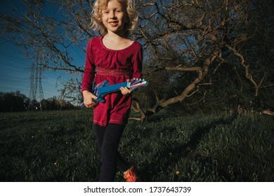 Cute Adorable Young Girl Playing Guitar Toy Outdoor. Girl Pretending To Be A Rock Music Star. Adorable Funny Child Having Fun In Park. Weird Funny Hilarious Authentic Candid Childhood Moments. 