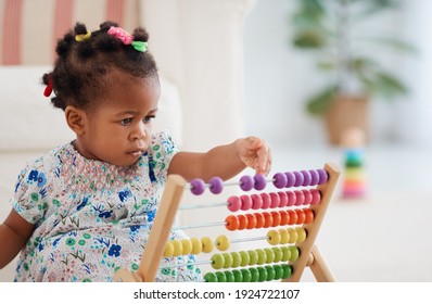 cute african american baby girl playing colorful abacus toy at home