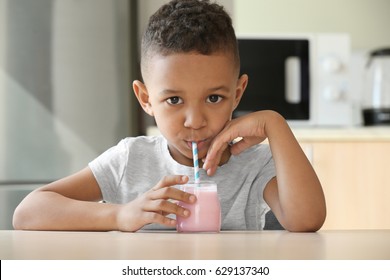 Cute African American boy drinking yogurt at home