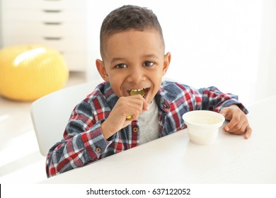 Cute African American boy eating yogurt at home