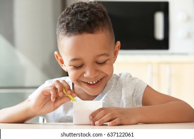 Cute African American boy eating yogurt at home