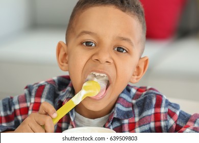 Cute African American boy eating yogurt at home, closeup