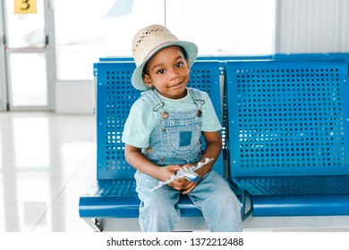 Cute African American Boy Sitting With Toy Plane In Airport