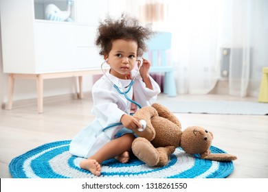 Cute African American Child Imagining Herself As Doctor While Playing With Stethoscope And Toy Bunny At Home