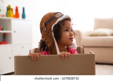 Cute African American Child Playing With Cardboard Box At Home