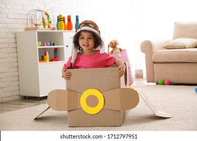 Cute African American Child Playing With Cardboard Plane At Home