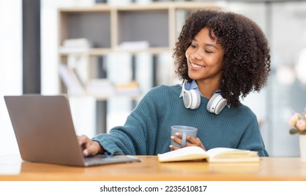 Cute african american female student wearing headphones with afro dreadlocks, studying remotely from home, using a laptop, taking notes on notepad during online lesson, e-learning concept,  - Powered by Shutterstock