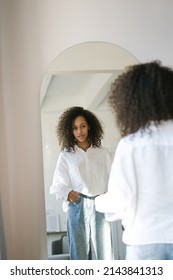 Cute African American Girl Choosing Clothes To Wear In Front Of Mirror In I The Living Room. Morning Wake Up Concept                              