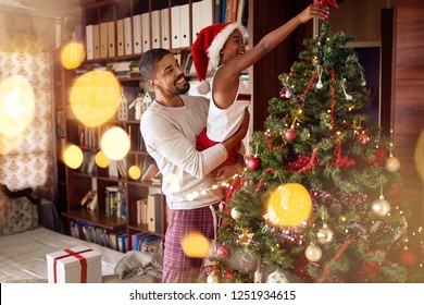 Cute African American Girl Decorating Christmas Tree With Smiling Father.
