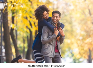 Cute African American Girl Jumped On Boyfriend Back, Having Fun While Walking By Autumn Forest, Copy Space