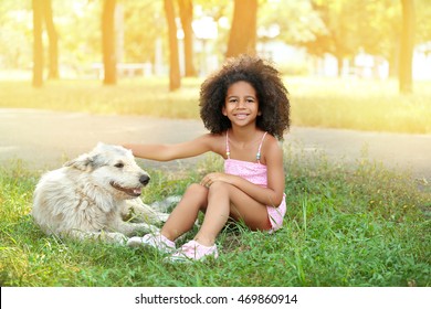 Cute African American Girl Playing With Dog In Park