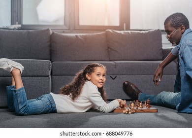 Cute African American Girl Playing Chess With Father On Floor At Home