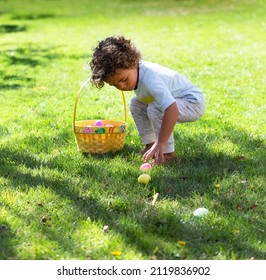 Cute African American little boy collecting Easter eggs outdoors during an Easter Egg hunt	