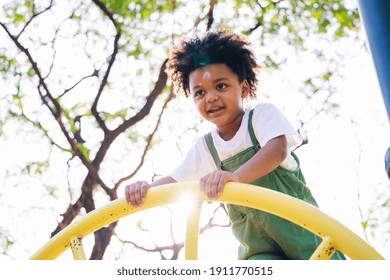 Cute African American little kid boy having fun while playing on the playground in the daytime in summer. Outdoor activity. Playing make believe concept. Outside education - Powered by Shutterstock