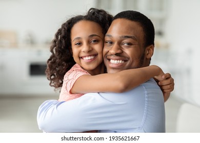 Cute african american school girl hugging her cheerful dad