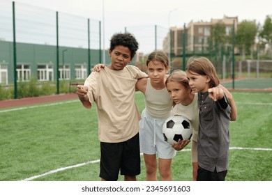 Cute African American schoolboy pointing forwards and explaining his classmates rules of game while standing on football field at stadium - Powered by Shutterstock