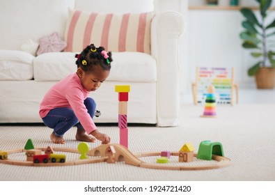 Cute African American Toddler Baby Girl Playing Wooden Toys On The Carpet At Home