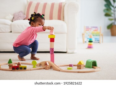Cute African American Toddler Baby Girl Playing Wooden Toys, Stacking The Tower Blocks On The Carpet At Home