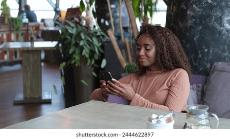 Cute African American woman using a mobile phone in a cafe - Powered by Shutterstock