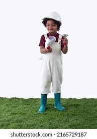 Cute African boy wearing white hardhat and gumboot holding roll of gesture like blue print under his arms, standing on the green grass wih white background.