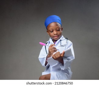 Cute African Career Girl Child Or Student In Laboratory Gown And With A Stethoscope, Acting Like Medical Practitioners Such As Doctor, Nurse Or Caregivers To Show The Benefit Of Science