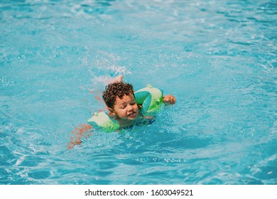 Cute African Toddler Boy Swimming In Pool With Inflatable Arm Rings