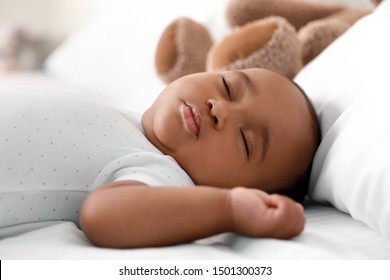 Cute African-American baby sleeping on bed