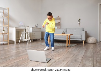 Cute African-American boy with laptop learning to dance at home