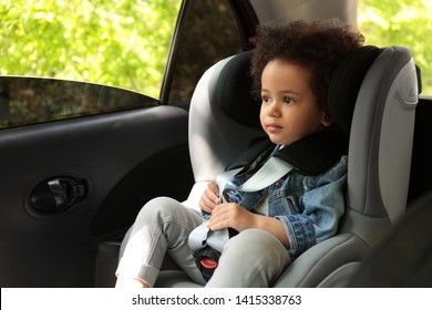 Cute African-American Child Sitting In Safety Seat Inside Car. Danger Prevention