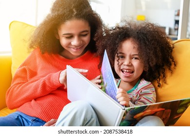 Cute African-American sisters reading book at home - Shutterstock ID 2087538418