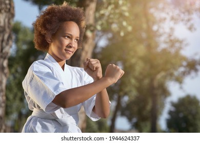 Cute Afro American girl practicing martial arts on sunny day in park