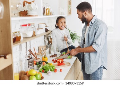 Cute Afro Kid Girl And Her Dad Cooking In Kitchen At Home. Happy Family Cooking Concept