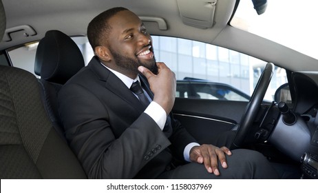 Cute Afro-American businessman looking in rear-view car mirror and smiling - Shutterstock ID 1158037969