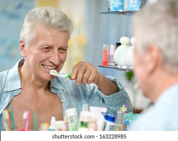 Cute Aged Guy Brushing His Teeth In Bathroom