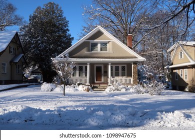 Cute arts & crafts bungalow style house on a winter day. Snow on the ground.                              