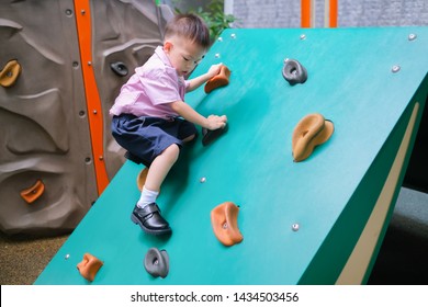 Cute Asian 2 - 3 Years Old Toddler Child Having Fun Trying To Climb On Artificial Boulders At Schoolyard Playground, Little Boy Climbing Up Rock Wall, Hand & Eye Coordination, Motor Skills Development