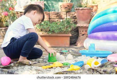 Cute Asian 4 - 5 Years Old Toddler Boy Playing With Sand Alone At Home, Kid Playing With Sand Toys In Urban Home Garden , Montessori Education, Creative Play For Kids Concept