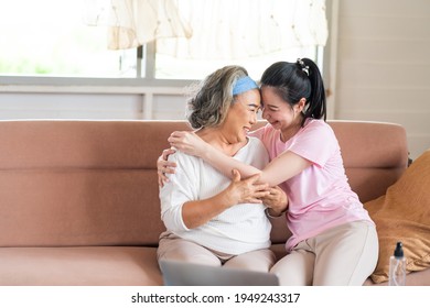 Cute Asian adult daughter embracing her mother with love in living room at home