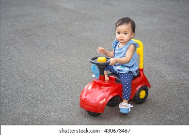 Cute asian baby girl drive a car toy in the park