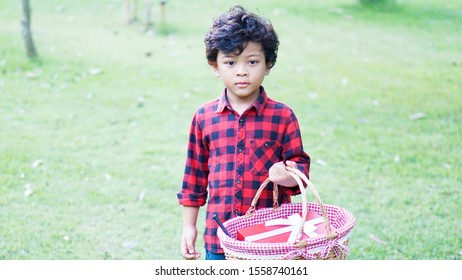 Cute Asian boy 6 year old holding basket in the park                           