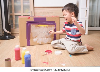 Cute Asian boy child enjoy using paintbrush painting on cardboard box at home, Fun art and crafts for little kids, Children's Art Project, DIY Toys from Recyclable Materials,  Home schooling concept