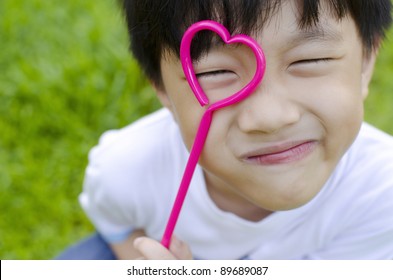 Cute Asian Boy Holding A Heart Shape On His Eye