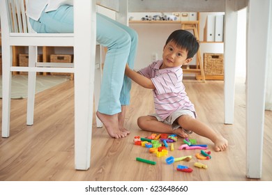 Cute Asian Boy Playing On The Floor When His Mom Is Working