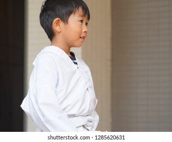 The Cute Asian Boy In Taekwando Uniform Is Listening To The Instructor.
