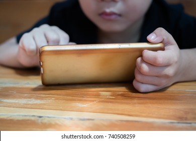 A Cute Asian Boy Is Using A Smartphone.Concepcion On The Problems Of Children With Smartphones.