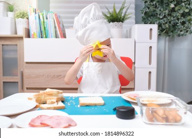 Cute Asian Boy Wearing Chef Hat And Apron Having Fun Preparing Sandwiches, Little Kid Making Cookie Cutter Sandwiches At Home, Cooking With Kids, Fun Indoor Activities For Kindergarten Concept