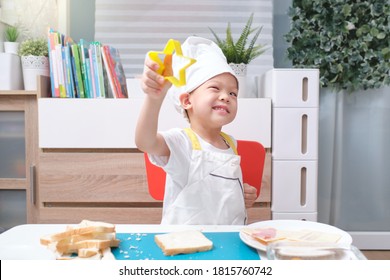 Cute Asian Boy Wearing Chef Hat And Apron Having Fun Preparing Sandwiches, Little Kid Making Cookie Cutter Sandwiches At Home, Cooking With Kids, Fun Indoor Activities For Kindergarten Concept